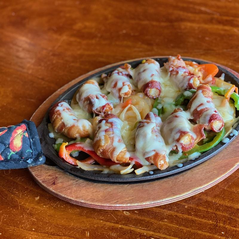 Bacon-wrapped shrimp sizzling on a cast-iron skillet at Hacienda Vieja